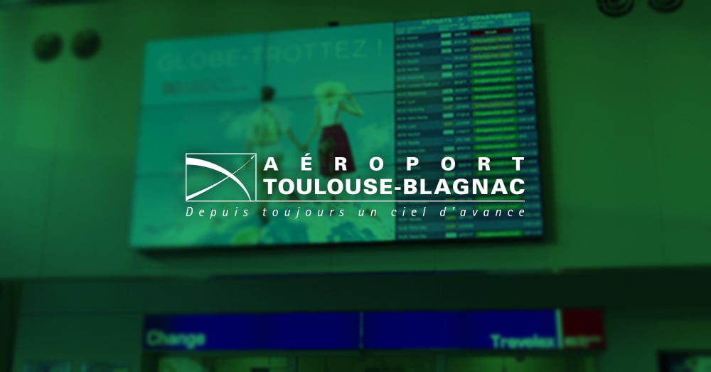 جدار فيديو في مطار تولوز بلانياك يعرض أوقات الإعلان والمغادرة للرحلات مع تراكب أخضر وشعار