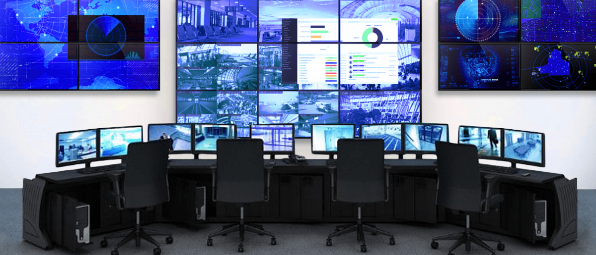 غرفة تحكم فارغة مع 4 محطات عمل و 3 جدران فيديو تعرض لقطات كاميرا الأمن الحية ولوحات معلومات البيانات