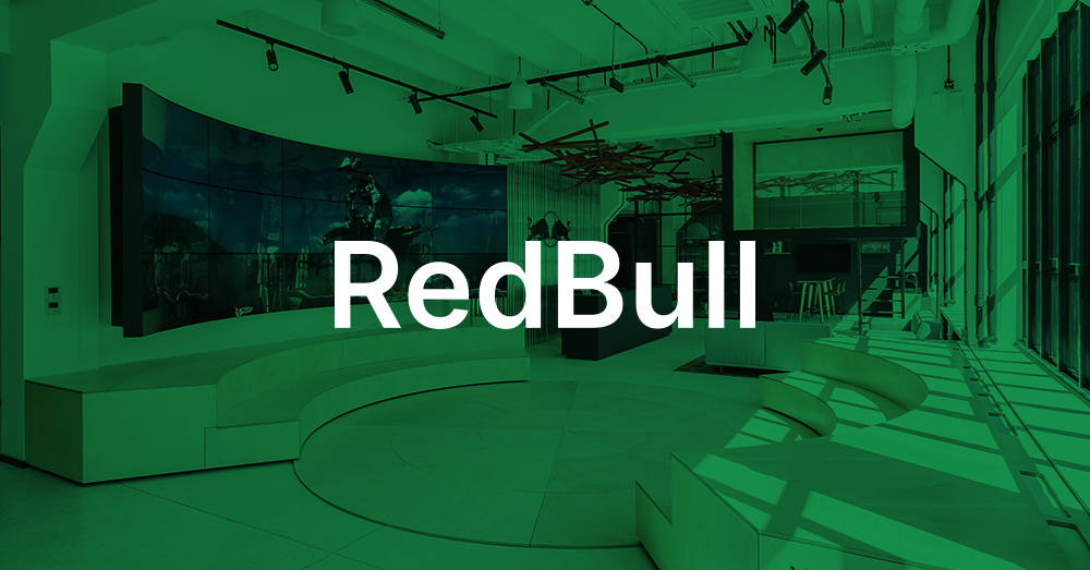 ردهة المقر الرئيسي لشركة Redbull Poland ، مع منطقة جلوس مغطاة بالدرج ومكتب استقبال وجدار فيديو منحني يعرض إعلان Red Bull التجاري مع تراكب أخضر وشعار